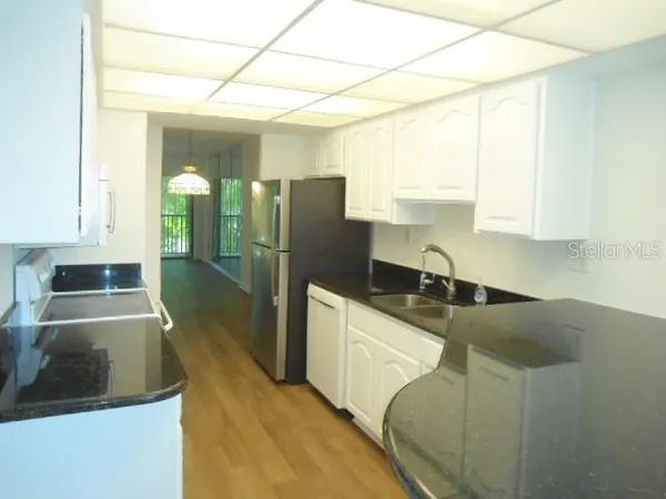 a kitchen with granite countertop a sink a stove and refrigerator