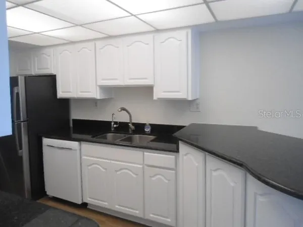 a kitchen with granite countertop white cabinets and refrigerator