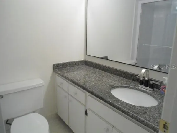 a bathroom with a granite countertop sink a toilet and a mirror