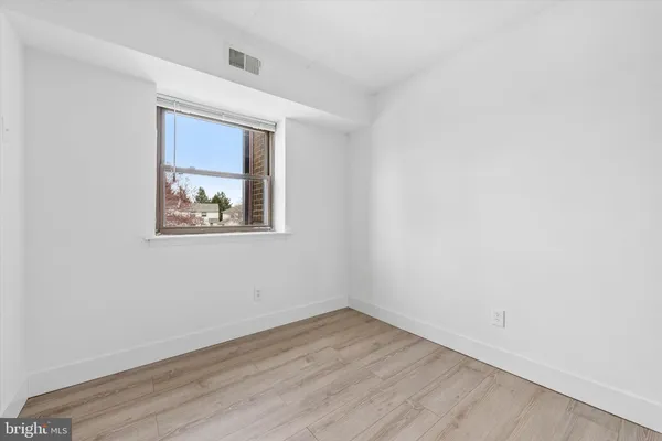 an empty room with wooden floor and window