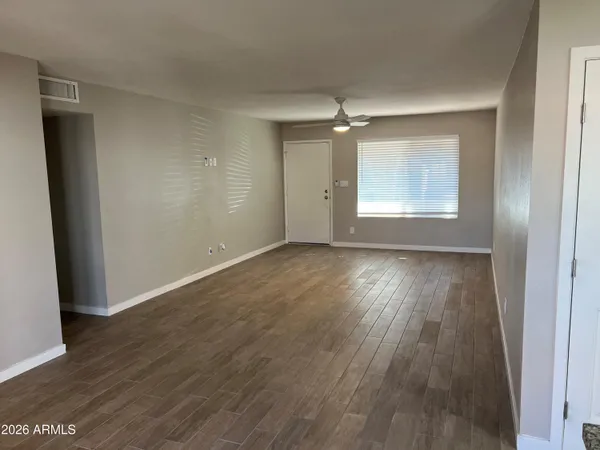 an empty room with wooden floor fan and windows