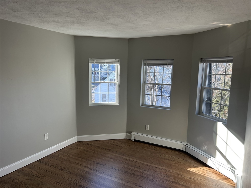 18 Ashcroft Street, Unit 301 Dedham, MA 02026 - Photo 12 of 14 an empty room with wooden floor and windows
