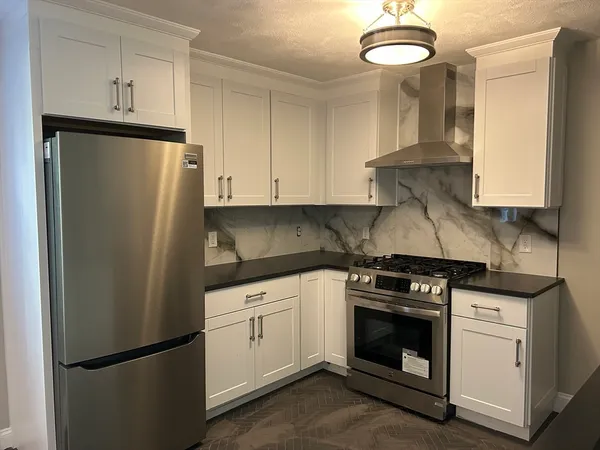 a kitchen with stainless steel appliances white cabinets and a refrigerator