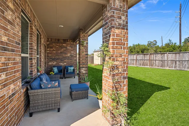 a view of a patio with couches chairs potted plants and wooden fence