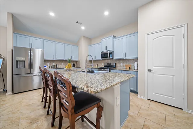 a kitchen with stainless steel appliances granite countertop a table chairs sink refrigerator and microwave
