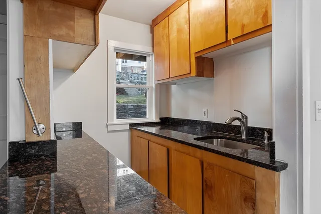 a kitchen with granite countertop a sink stove and cabinets