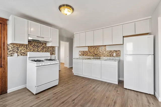 a kitchen with white cabinets and appliances