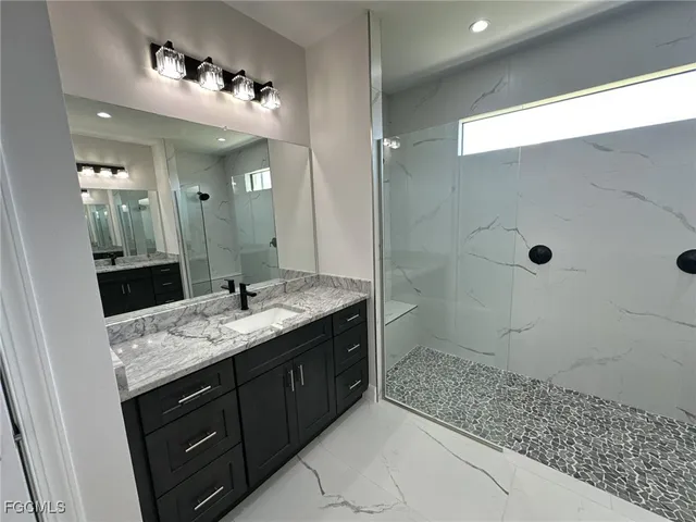 a bathroom with a granite countertop sink a mirror and shower