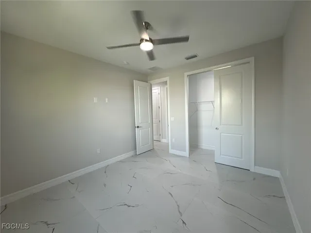 an empty room with closet and a chandelier fan
