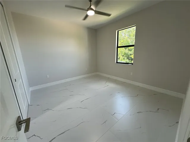 an empty room with windows and fan