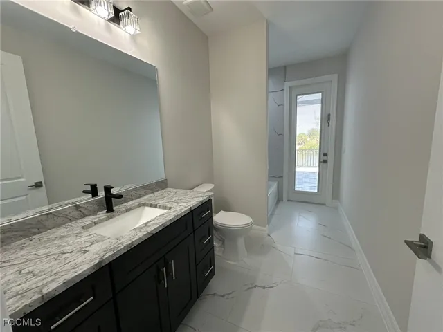 a bathroom with a granite countertop sink a toilet and a mirror