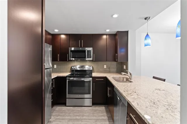 a kitchen with stainless steel appliances granite countertop a sink stove and refrigerator