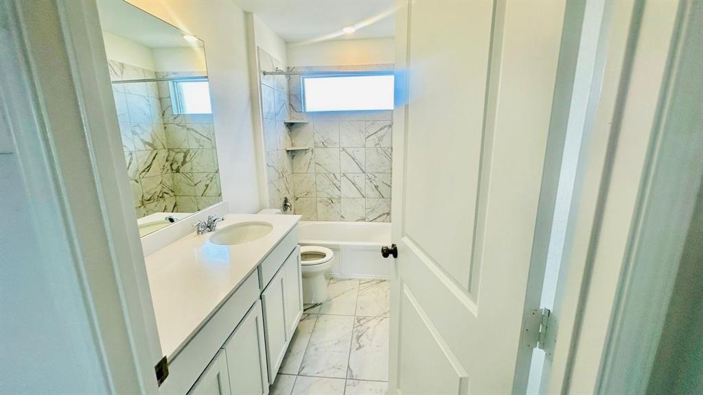 192 Rodney Boat Road Kyle, TX 78640 - Photo 23 of 38 Marble-look tile and a white vanity create a clean, contemporary bathing space.