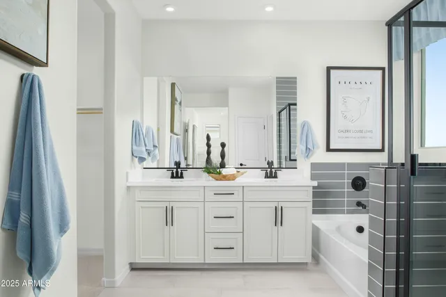a bathroom with a double vanity sink a mirror a bathtub and shower