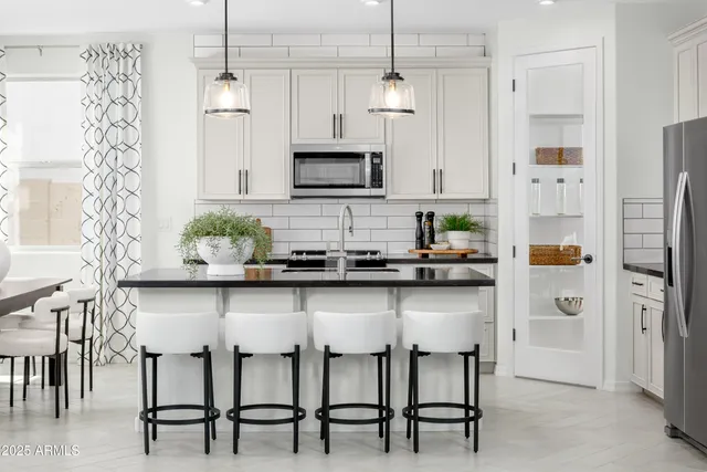 a kitchen with stainless steel appliances a table chairs refrigerator and microwave