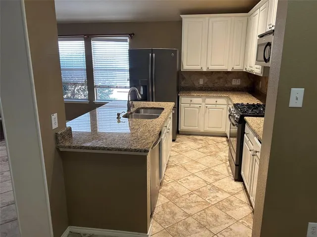 a kitchen with stainless steel appliances granite countertop a stove a sink and a refrigerator