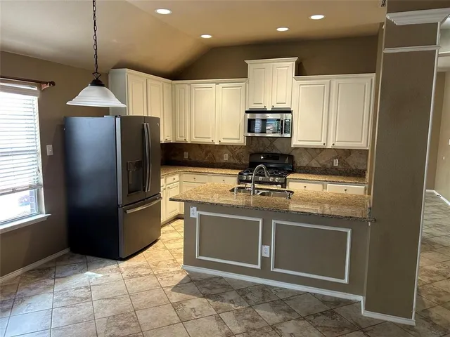 a kitchen with stainless steel appliances granite countertop a refrigerator a stove a sink and a microwave