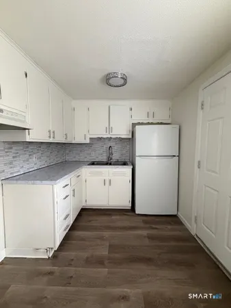 a kitchen with granite countertop white cabinets and white appliances