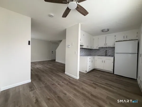 a view of a kitchen with a refrigerator a ceiling fan and wooden floor