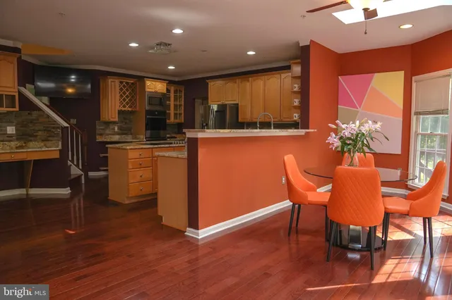 a open kitchen with stainless steel appliances granite countertop a stove a refrigerator a sink a dining table and chairs with wooden floor