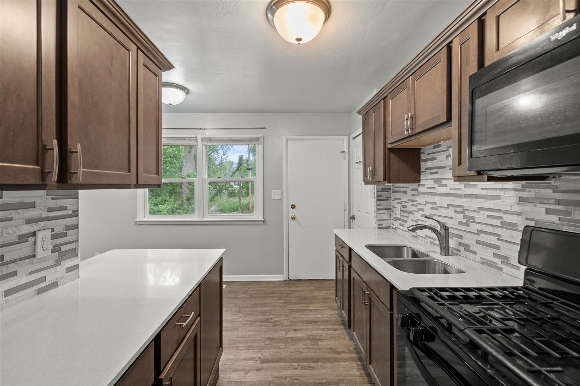 6715 East 3rd Avenue Gary, IN 46403 - Photo 17 of 25 a kitchen with a sink stove top oven and cabinets