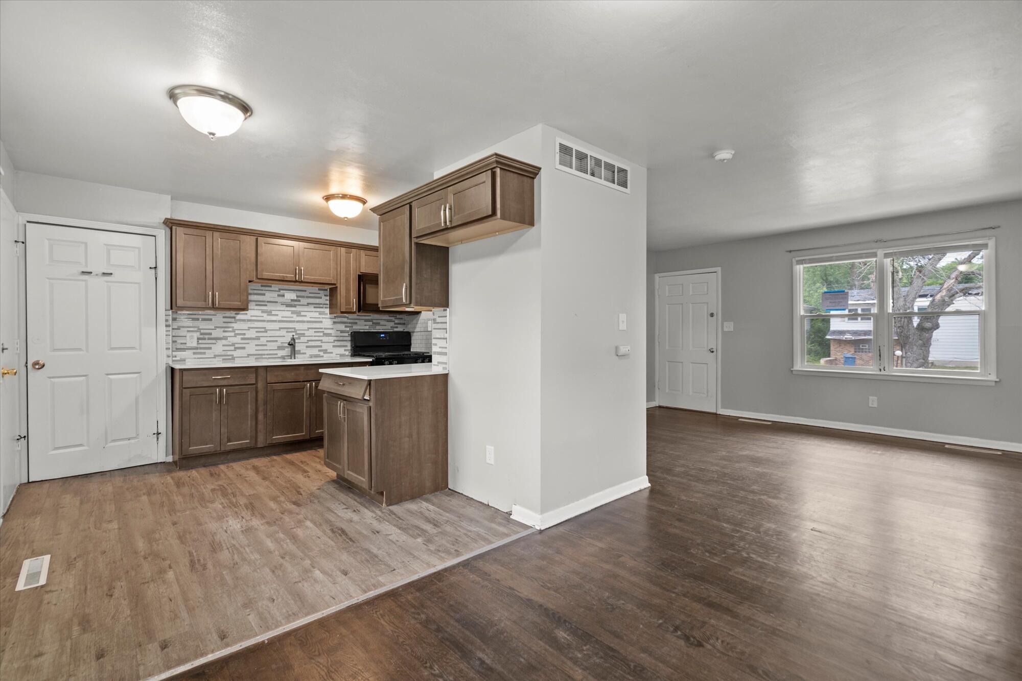 6715 East 3rd Avenue Gary, IN 46403 - Photo 18 of 25 a kitchen with a refrigerator a stove top oven a sink dishwasher and white cabinets with wooden floor