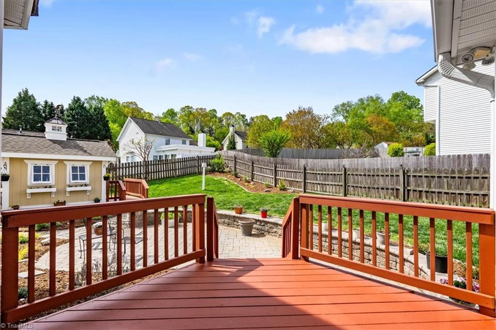 3303 Bardwell Road Greensboro, NC 27410 - Photo 41 of 50 View from the sunroom to the backyard complete with a picket fence, garden spots, large stone patio, deck and charming gardening shed.