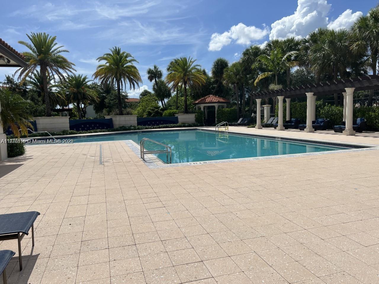 1415 Southwest 113th Avenue, Unit 1415 Pembroke Pines, FL 33025 - Photo 43 of 44 a view of swimming pool with table and chairs under an umbrella