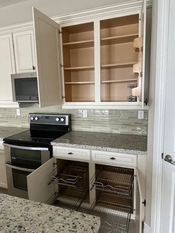 a view of kitchen with a stove and a microwave