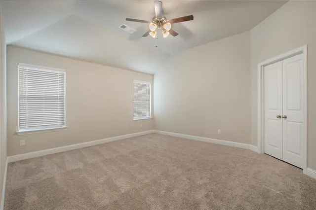 an empty room with a chandelier fan and windows