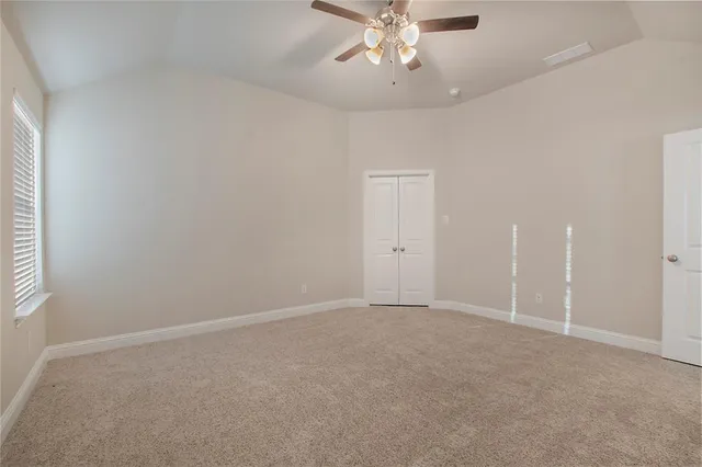 an empty room with a chandelier fan and windows
