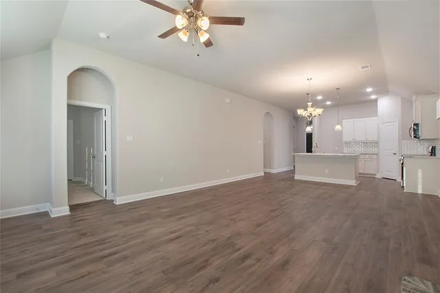 a view of a livingroom with a fireplace a chandelier fan and wooden floor