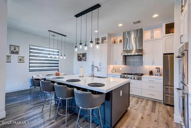 a kitchen with stainless steel appliances kitchen island granite countertop a table chairs stove and white cabinets
