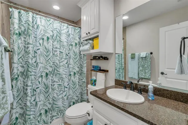 a bathroom with a granite countertop sink a toilet and shower curtain