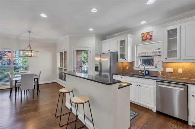 a kitchen with stainless steel appliances granite countertop a stove top oven a sink a dining table and chairs