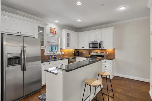 a kitchen with stainless steel appliances granite countertop a refrigerator a stove a sink and a microwave