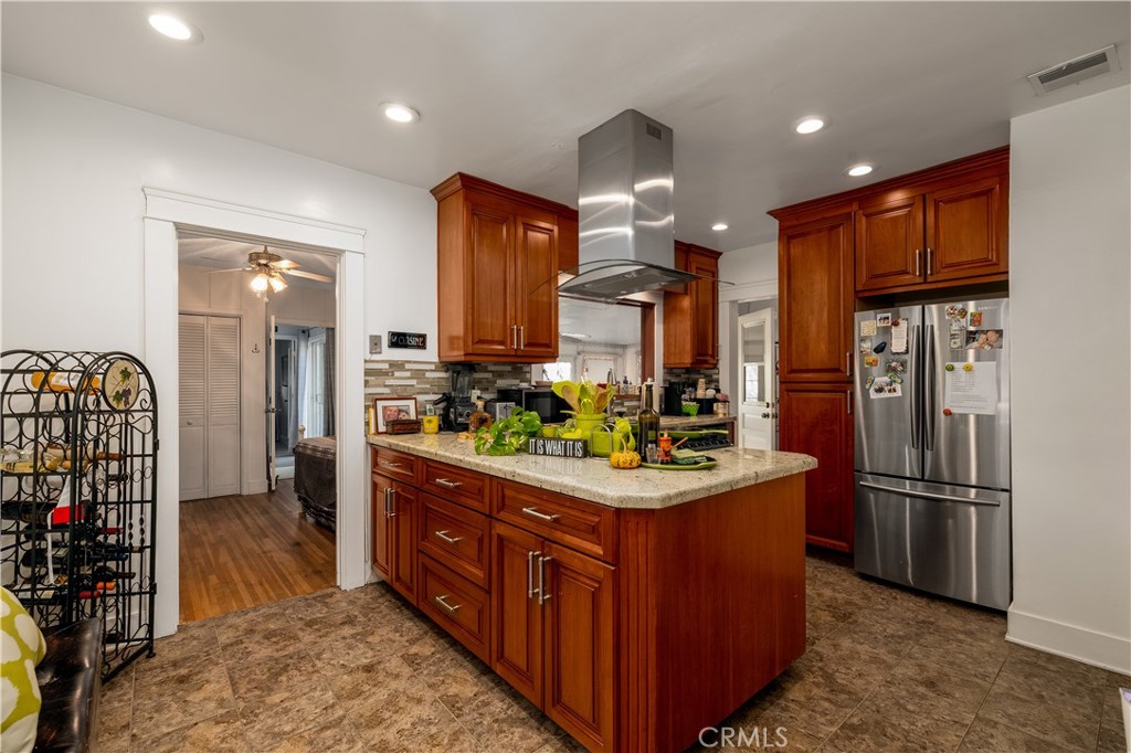 3642 Larchwood Place Riverside, CA 92506 - Photo 15 of 35 a kitchen with stainless steel appliances kitchen island granite countertop a refrigerator a stove and a sink