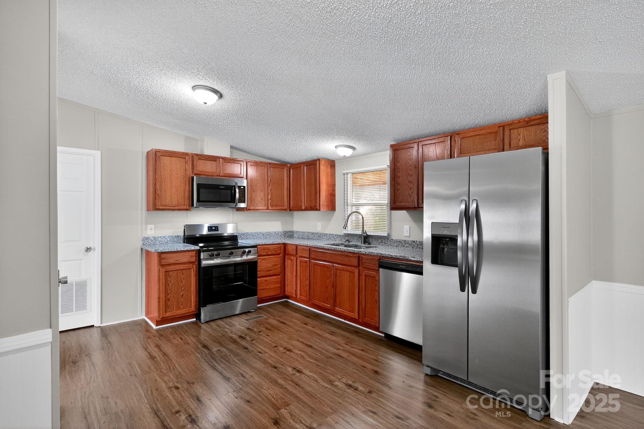 3802 Hickory Grove Road Mount Holly, NC 28120 - Photo 5 of 15 a kitchen with stainless steel appliances granite countertop a refrigerator a stove top oven a sink and dishwasher with wooden floor