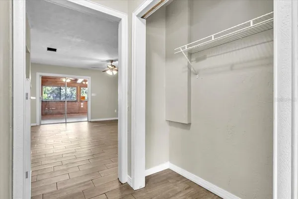 a view of an empty room with wooden floor and a ceiling fan