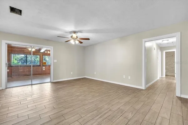 a view of an empty room with a window and wooden floor