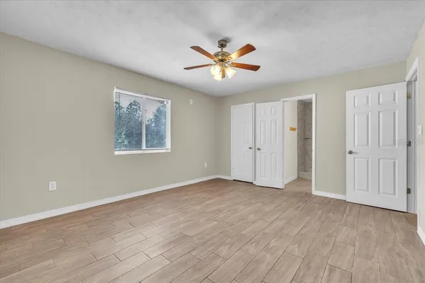 a view of an empty room and chandelier fan