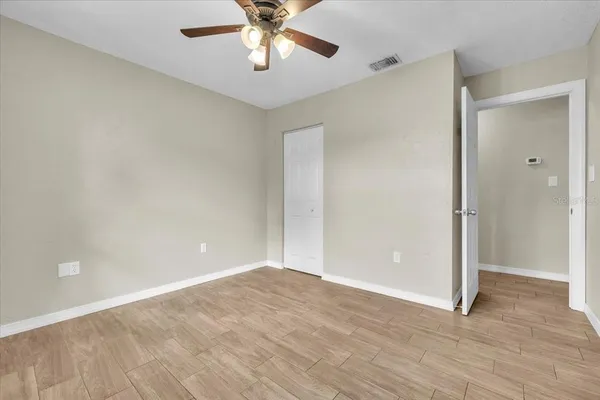 an empty room with wooden floor and a ceiling fan
