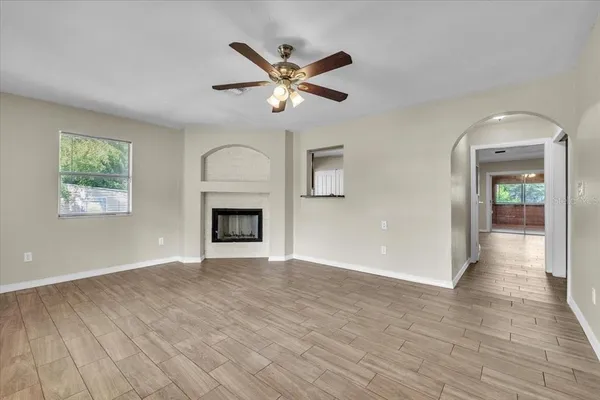 a view of an empty room with chandelier fan and wooden floor
