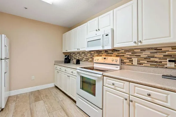 a kitchen with granite countertop white cabinets and white appliances