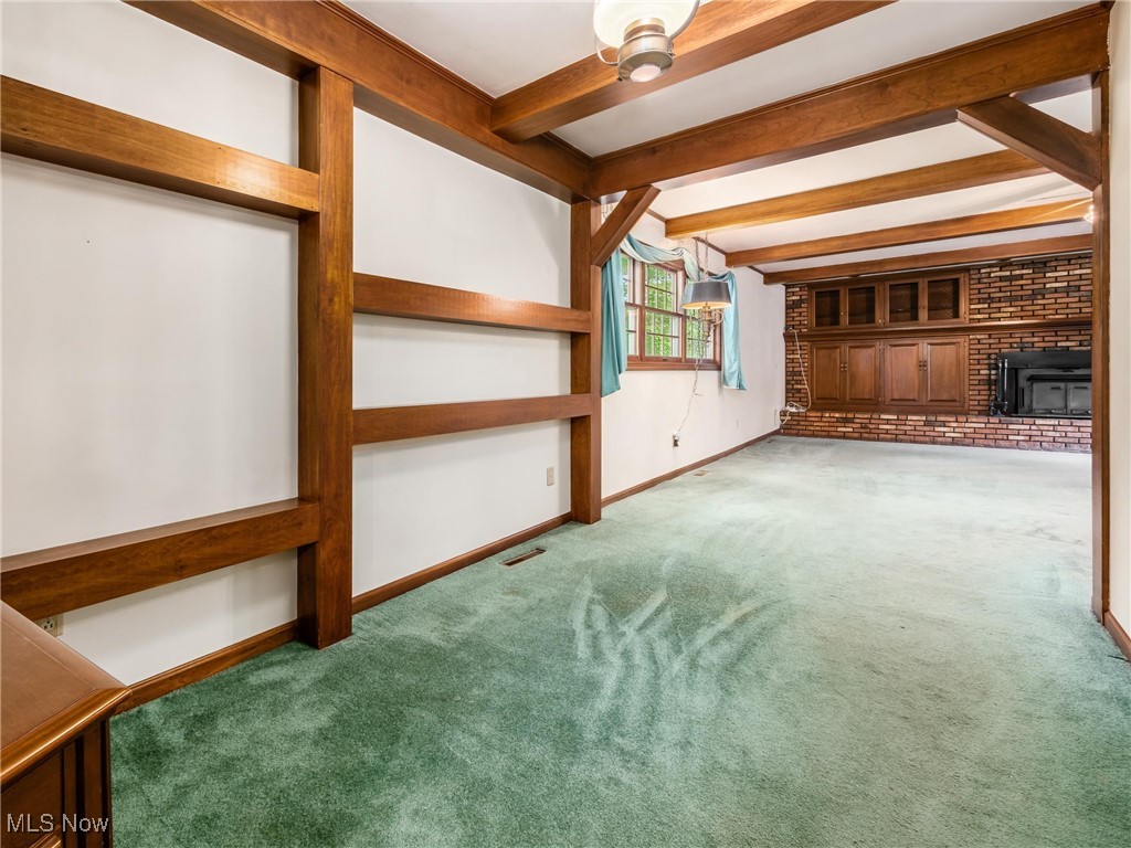 975 Richey Road Zanesville, OH 43701 - Photo 11 of 27 Unfurnished living room featuring carpet, beamed ceiling, baseboards, and a ceiling fan
