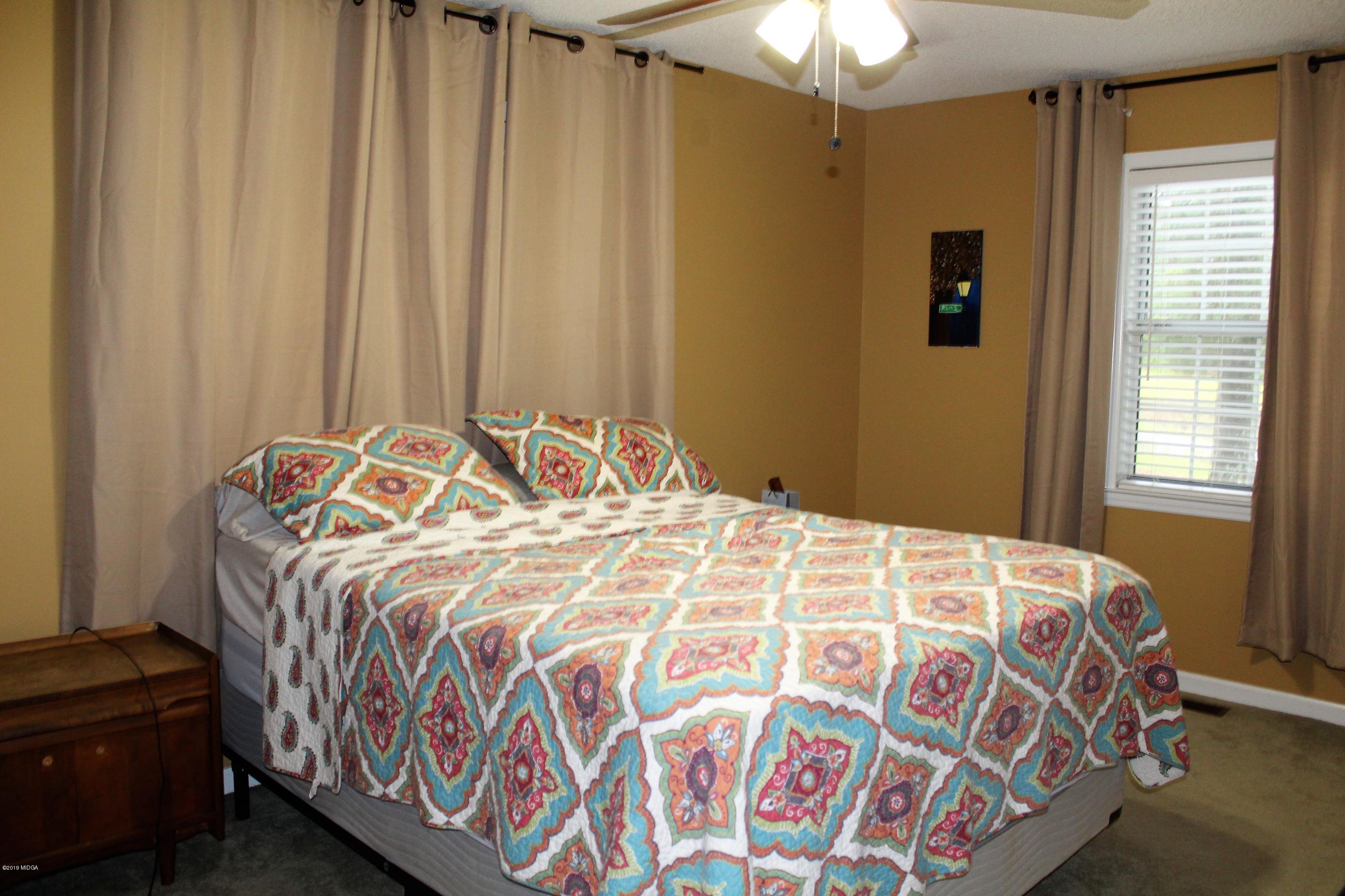 139 Bone Creek Road Macon, GA 31211 - Photo 10 of 18 a bedroom with a bed and a chandelier