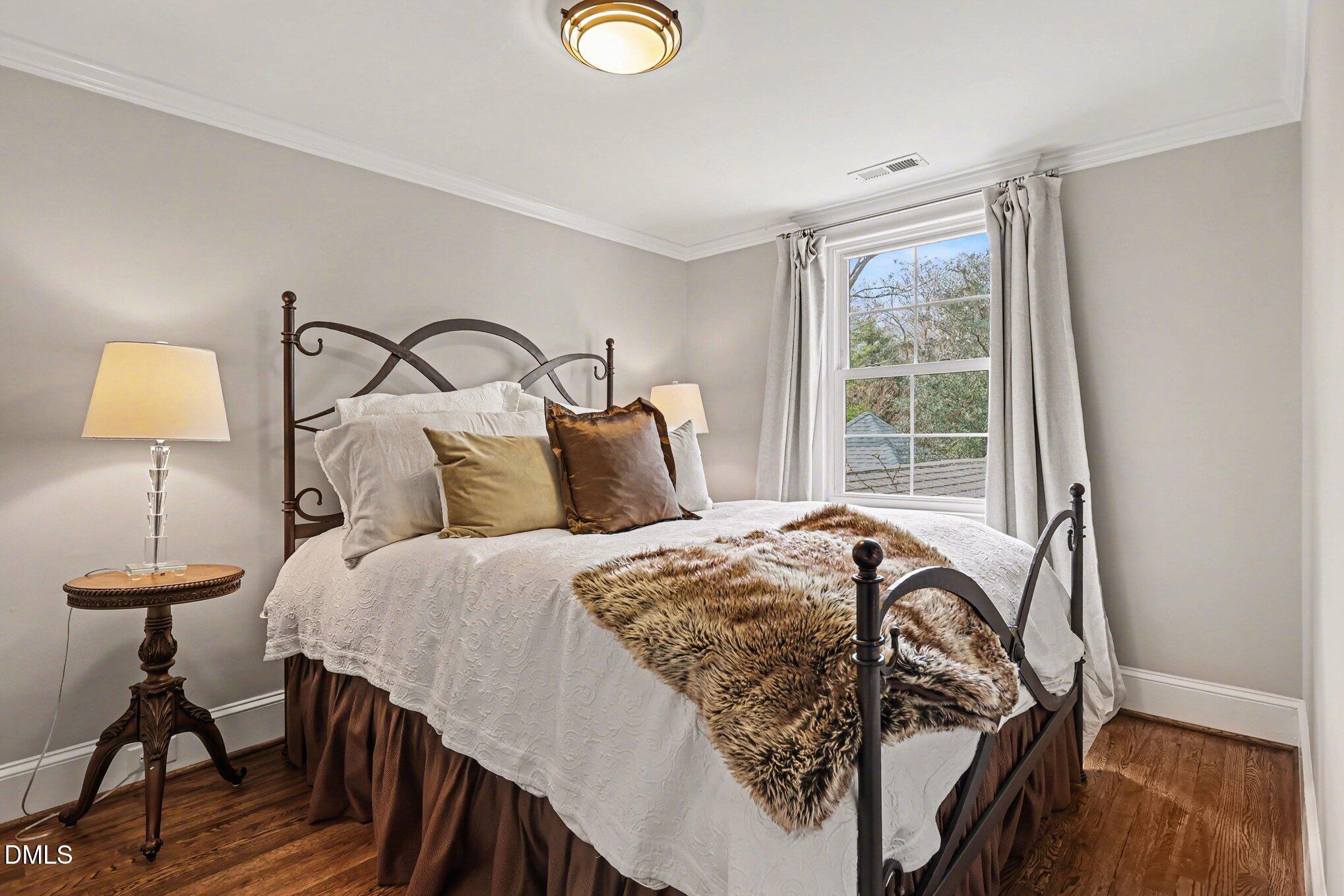 227 Furches Street Raleigh, NC 27607 - Photo 22 of 26 a bedroom with a bed and a lamp next to a window