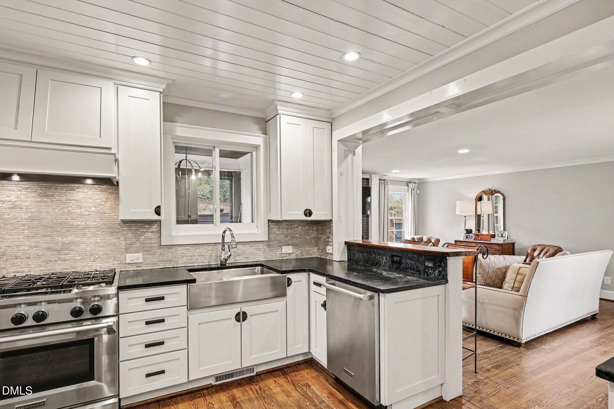 227 Furches Street Raleigh, NC 27607 - Photo 9 of 26 a kitchen with granite countertop a stove a sink and white cabinets