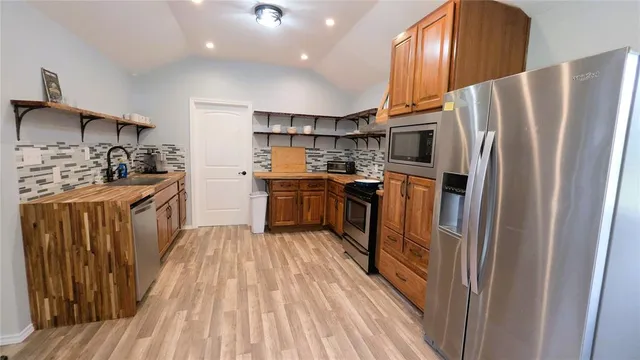 a kitchen with stainless steel appliances granite countertop a refrigerator a stove a sink and a cabinets