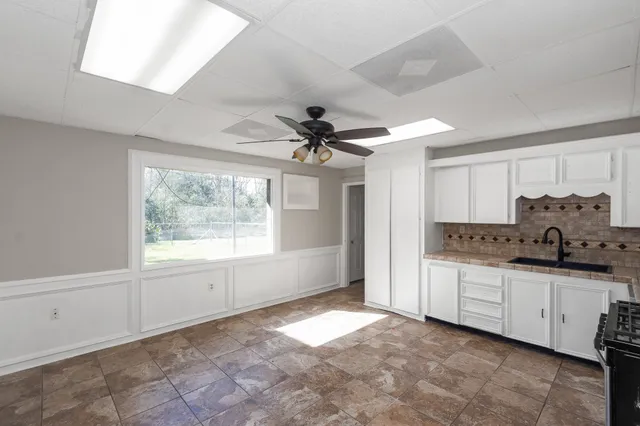 a kitchen with a stove a refrigerator and white cabinets